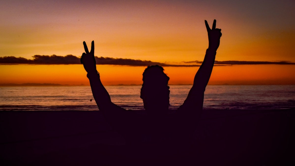 a person on a beach with their hands in the air